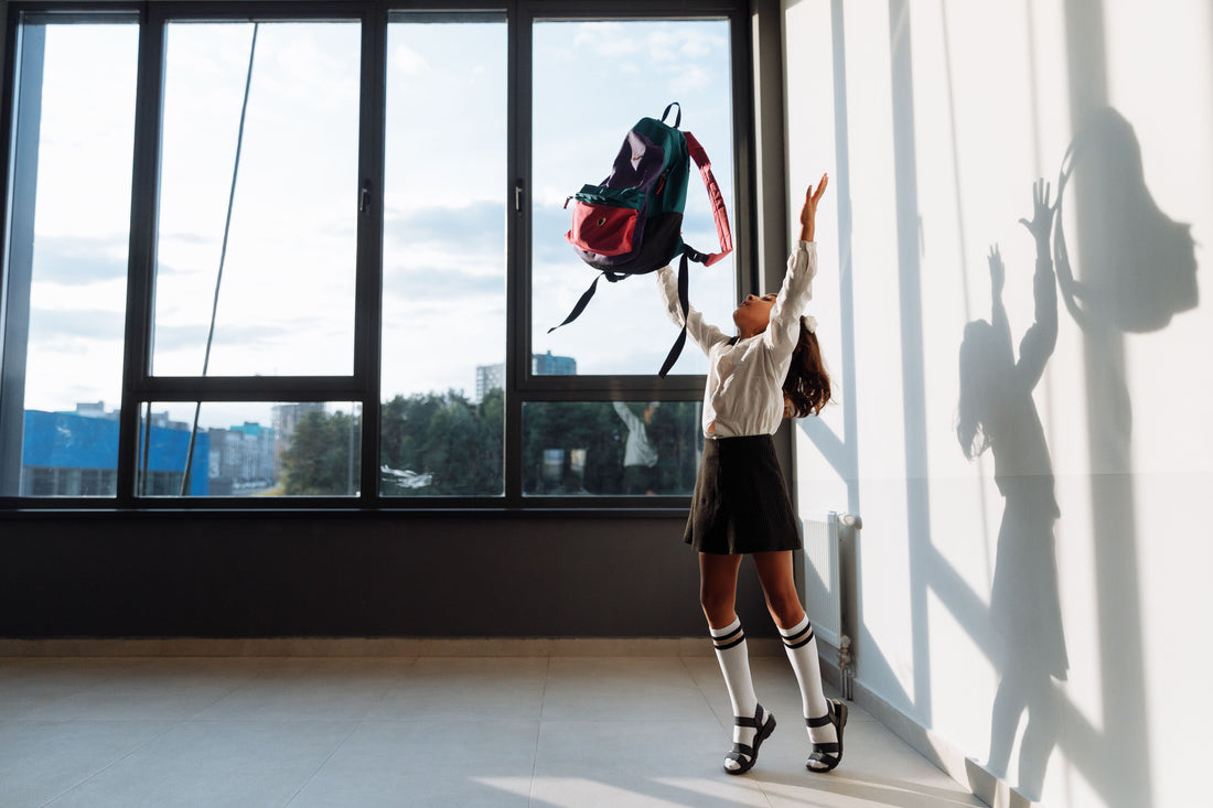 Schoolgirl throwing her bag in the air
